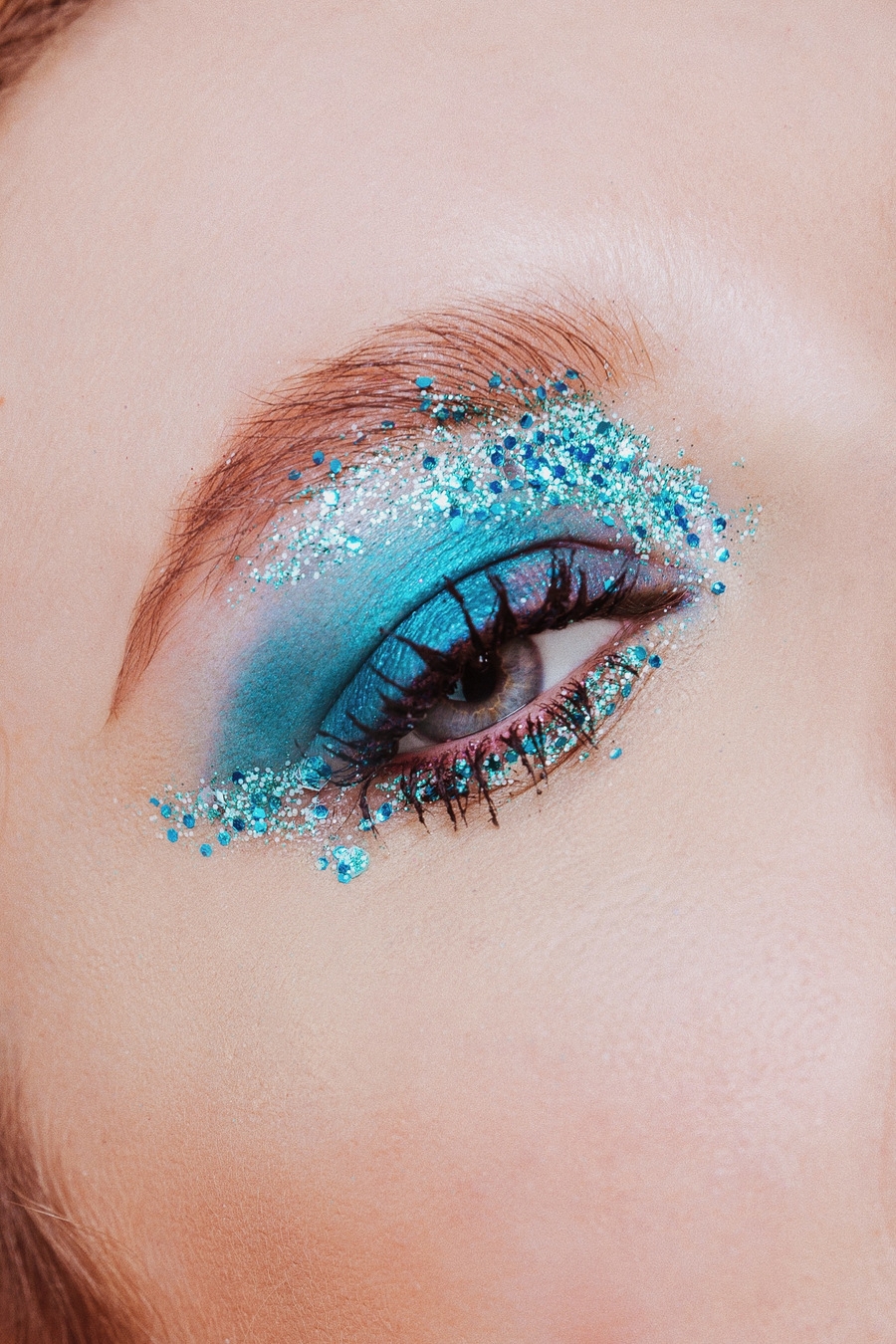 A person wearing blue eye shadow with glittery particles