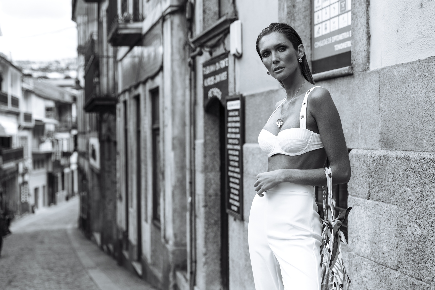 A woman standing in the middle of a road holding her handbag