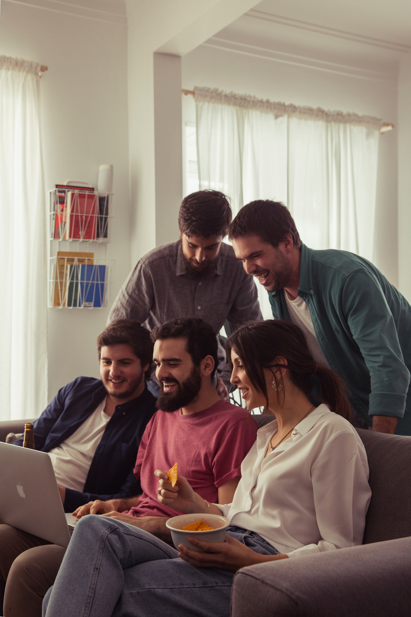 6 friends have fun in a room, 1 has a laptop and the others enjoy popcorn