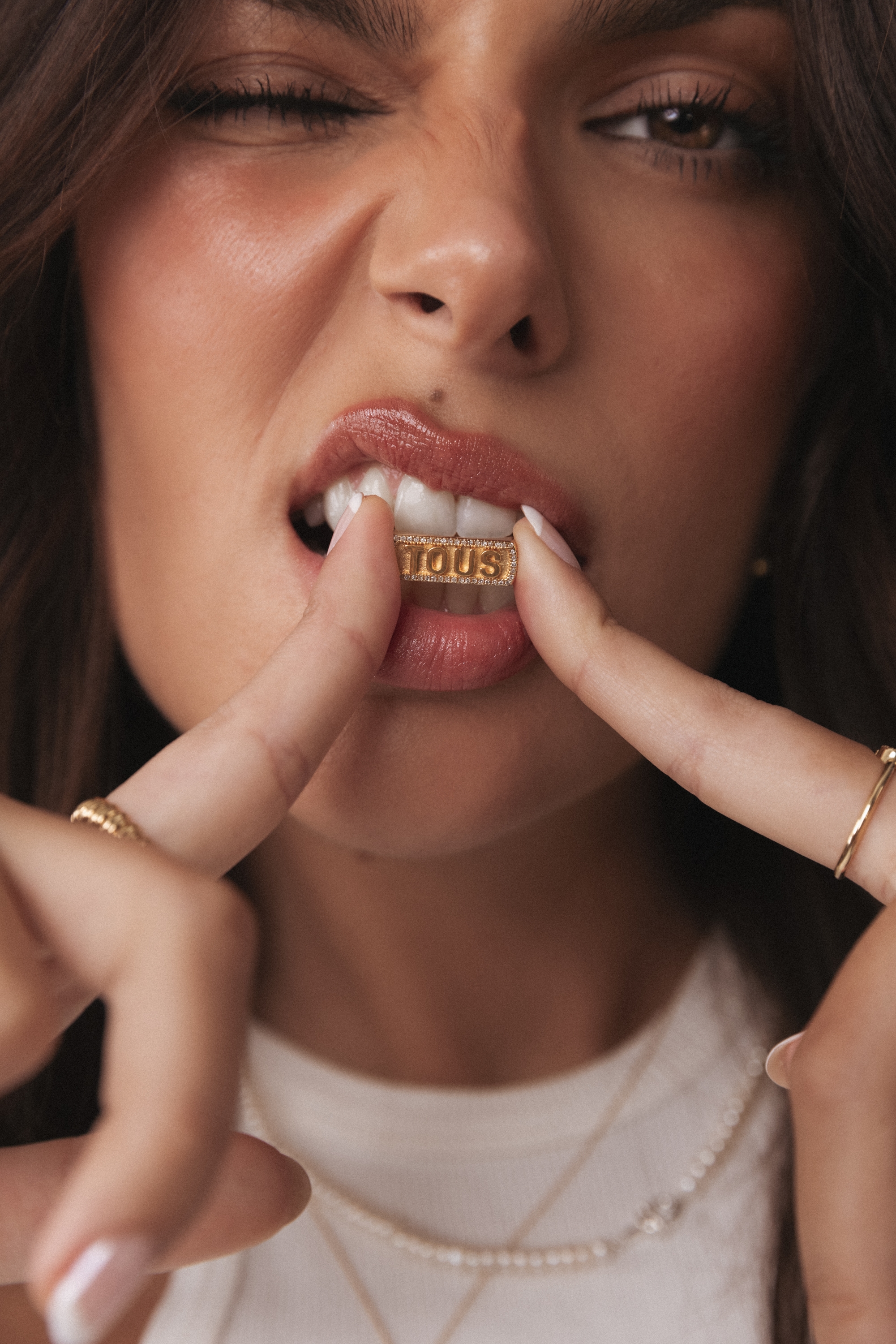 A woman is wearing a gold necklace and sticking out her tongue, she has a gold ring in her mouth, and it appears as if she is trying to eat the ring
with her tongue