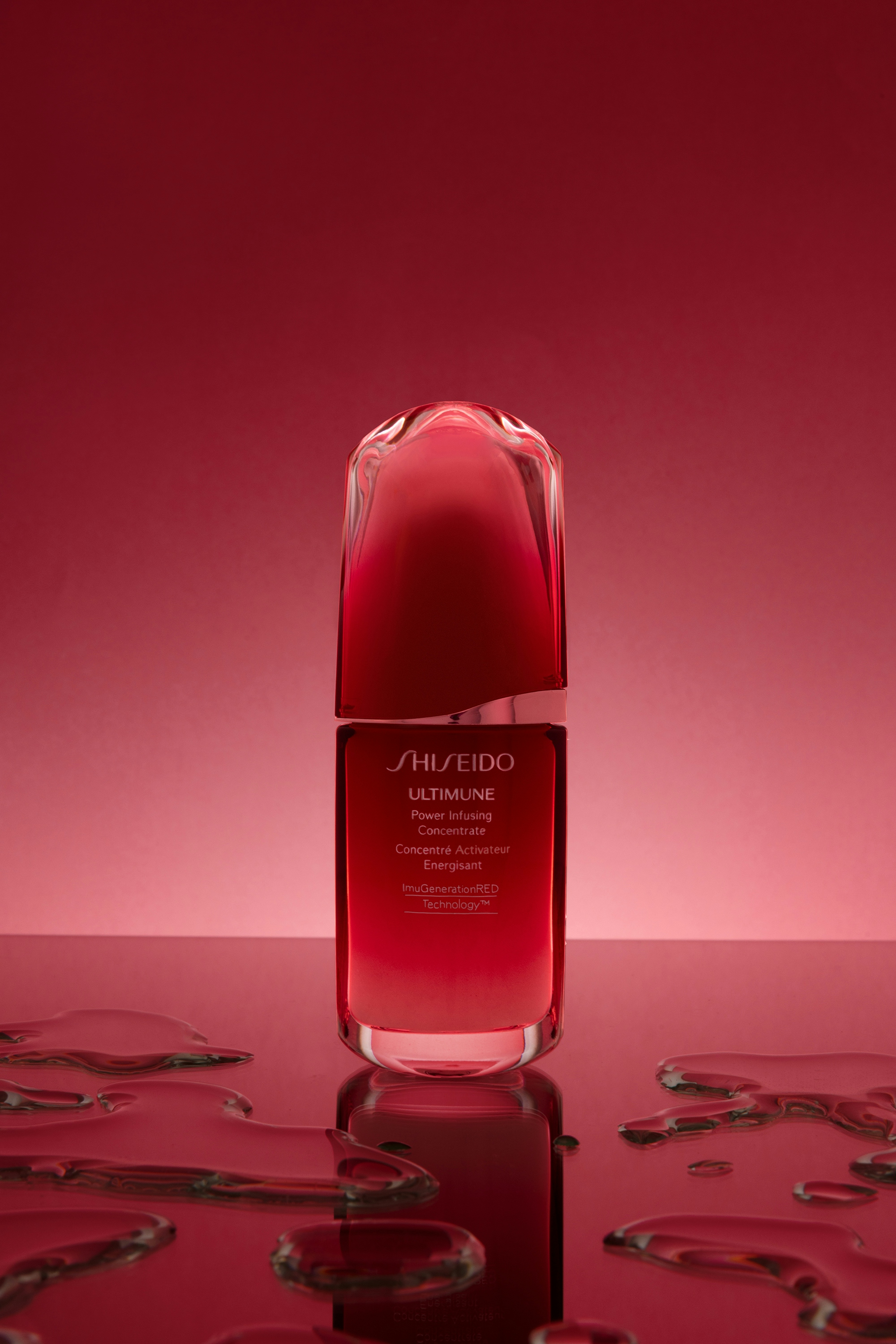 A bottle of liquid on a red table, with drops of water all over the surface