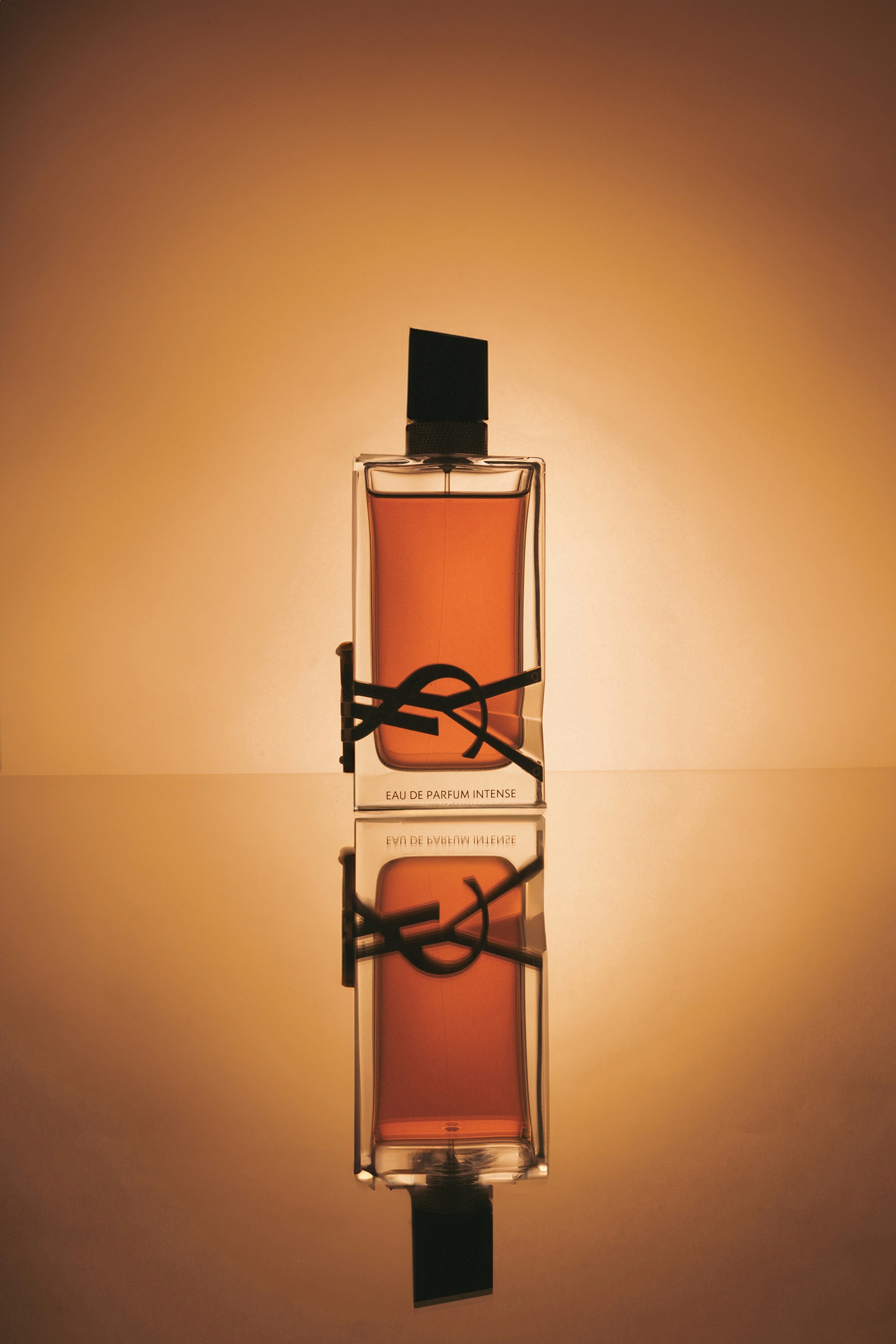 A bottle of cologne on a table with reflective surfaces that cause the reflection effect