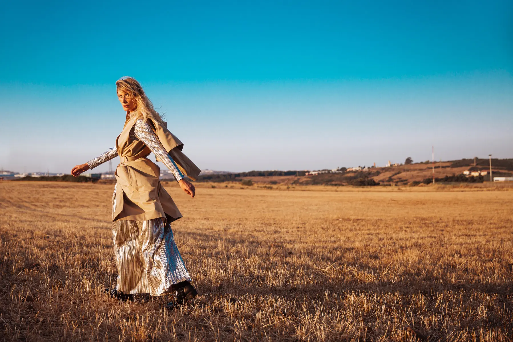 Astrid Werdnig in a long dress walking through a field, being photographed by KAT V Photography.