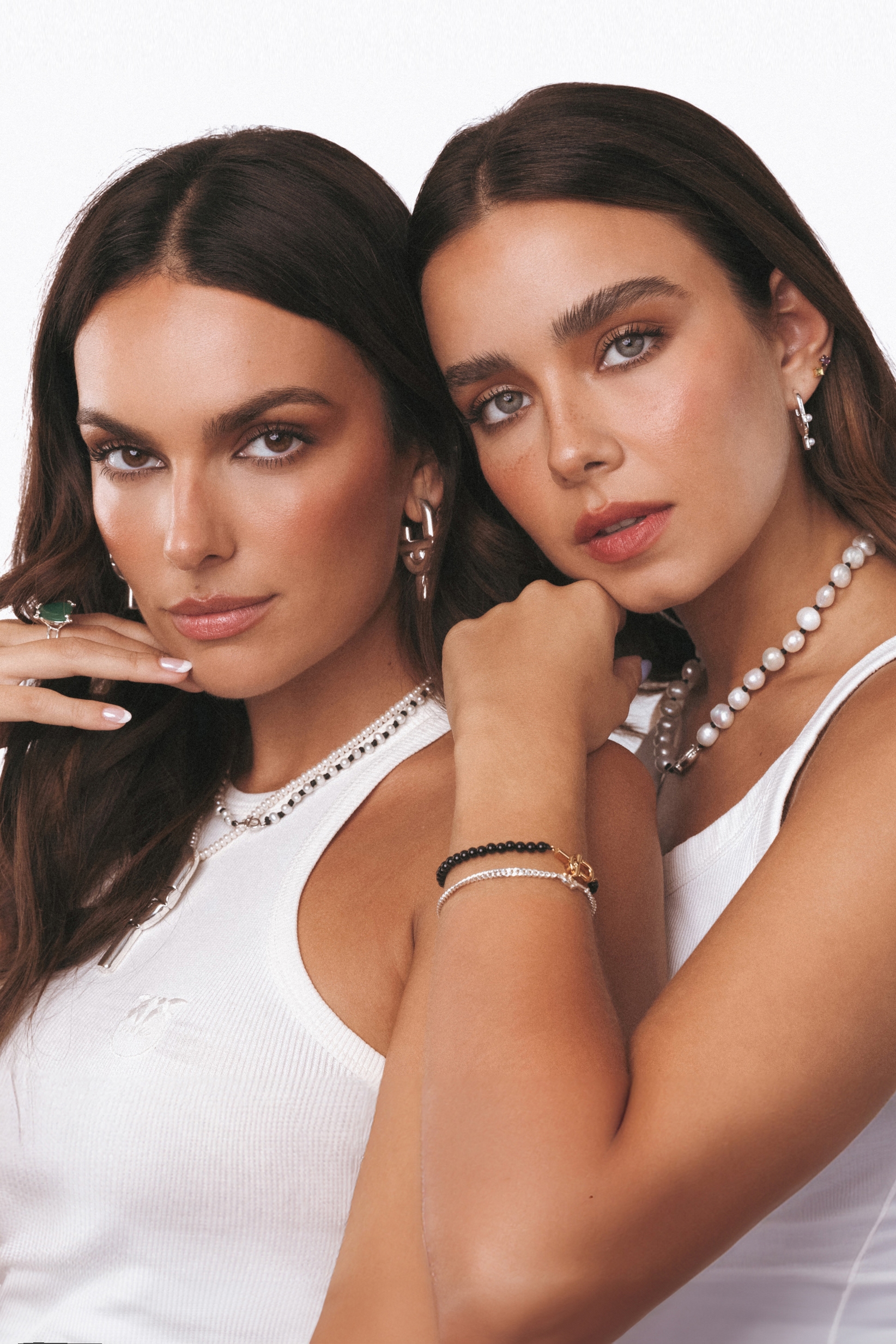 2 women standing together with one on the left and another in white shirt to the
right, both wearing earrings